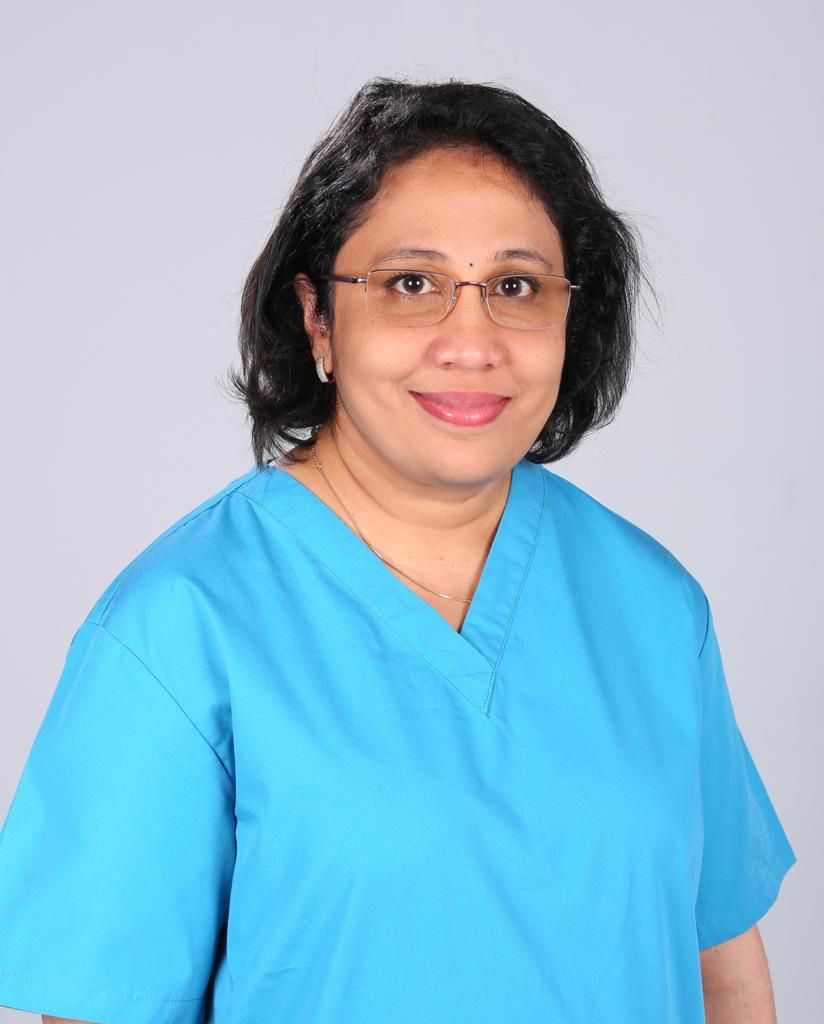 A professional headshot of Dr. Vimi, a top dermatologist in Calicut, wearing blue medical scrubs.