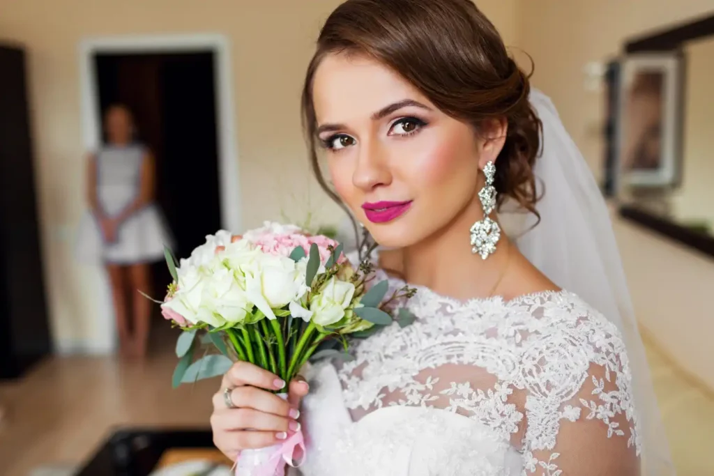 Beautiful bride with elegant makeup and floral bouquet, showcasing flawless skin and bridal glow.